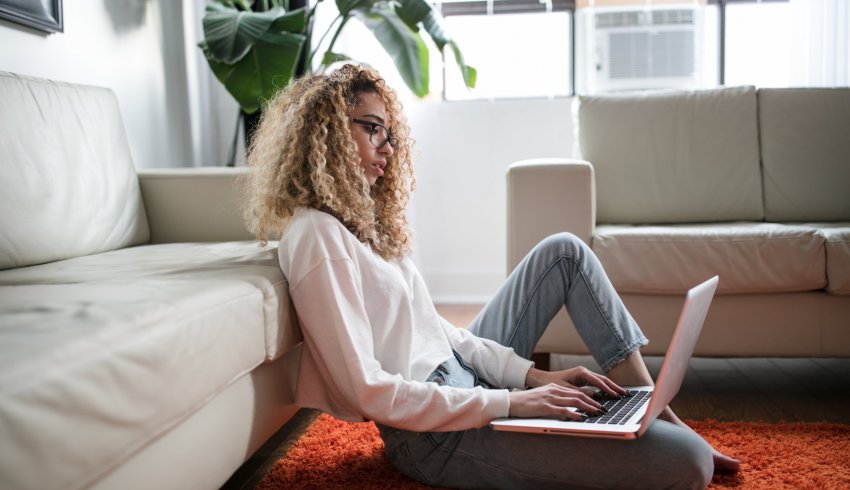 une femme assise sur un tapis avec l'ordinateur portable sur ses genoux